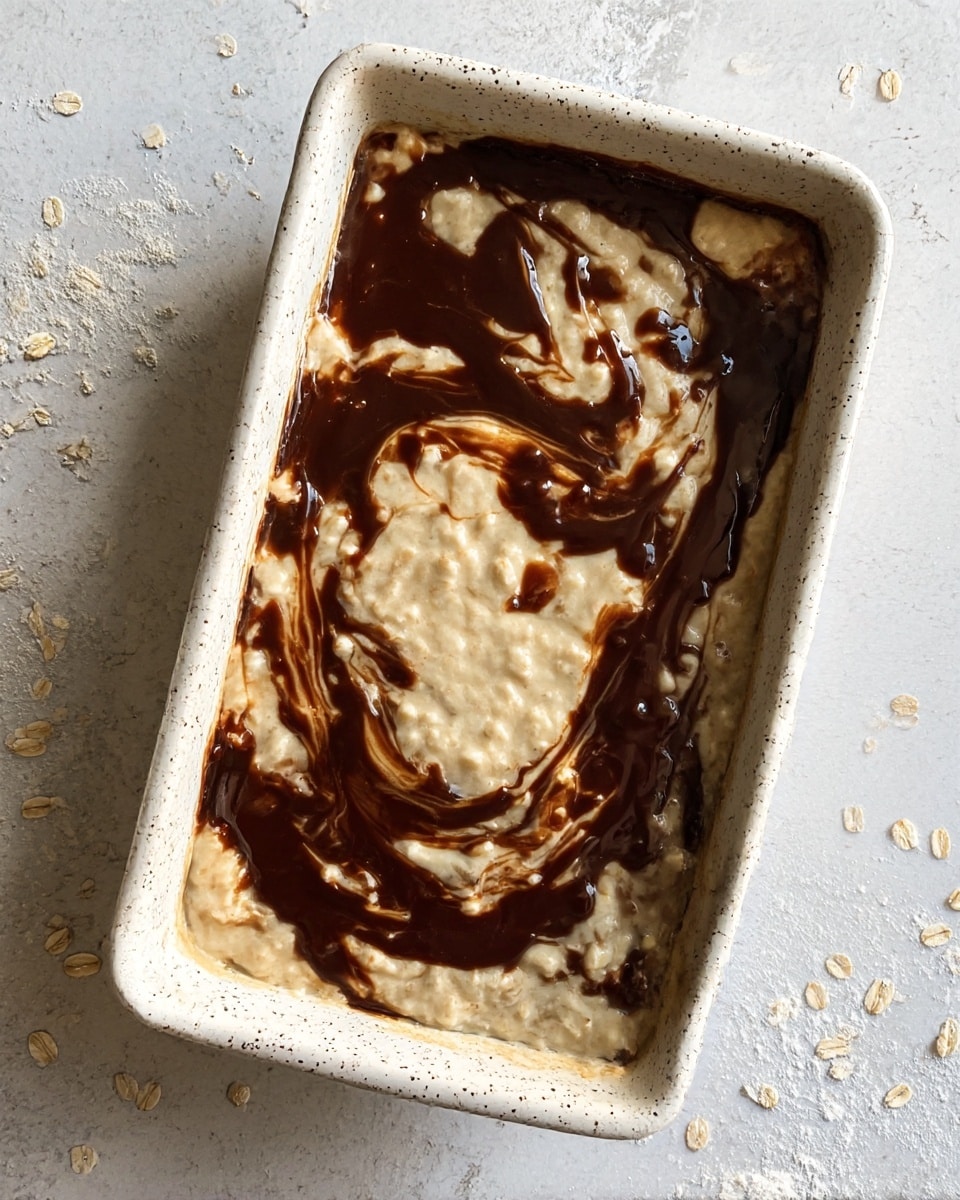The dish is in a speckled white rectangular baking dish, showing two main layers. The bottom layer is creamy and pale beige with a slightly chunky texture, likely oatmeal or porridge. The top layer is swirled in dark brown sauce or syrup, creating a marbled effect over the light base. The creamy layer spreads evenly across the dish, while the dark layer flows in thick, uneven ribbons over the surface. The dish is placed on a white marbled textured surface with a few scattered oats and small white powder bits around it. photo taken with an iphone --ar 4:5 --v 7