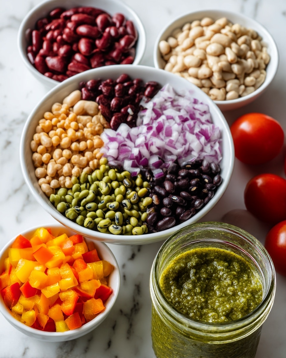 A white bowl filled with seven sections, each holding a different type of bean or legume: light beige, dark red, green, yellow, black, black-eyed peas, and dark brown, arranged in a circular pattern around a center of finely chopped purple onions. Next to it, there is a small white bowl filled with small diced yellow, orange, and red bell peppers. In the foreground, a glass jar holds a thick green sauce with a textured surface. Two small red tomatoes are partially visible on the right side. All items sit on a white marbled surface. Photo taken with an iphone --ar 4:5 --v 7