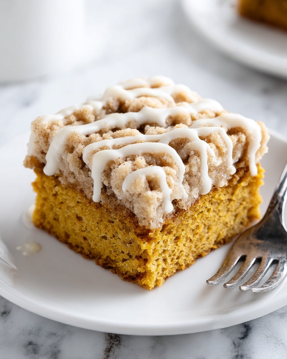 A square piece of cake is placed on a white plate on a white marbled surface. The cake has two main layers: a bottom layer of moist, golden-brown pumpkin cake with a soft texture, and a thick crumbly topping of light beige streusel with a coarse texture. Drizzled over the top is a smooth, white glaze in thin lines. A silver fork rests next to the cake on the plate. Photo taken with an iphone --ar 4:5 --v 7