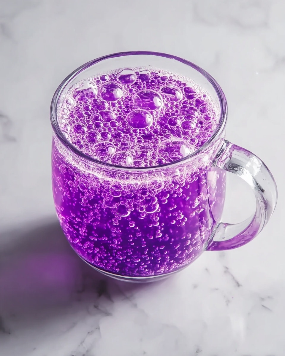 A close-up image shows dark purple liquid being poured from a clear glass carafe into a transparent glass bowl. The liquid has a smooth, glossy surface with gentle ripples where it flows into the bowl. The bowl sits on a white marbled surface, which adds a clean bright background. In the background, there is a blurry green plant in a white pot. A woman's hand is holding the carafe from the top right corner of the image. Photo taken with an iphone --ar 4:5 --v 7