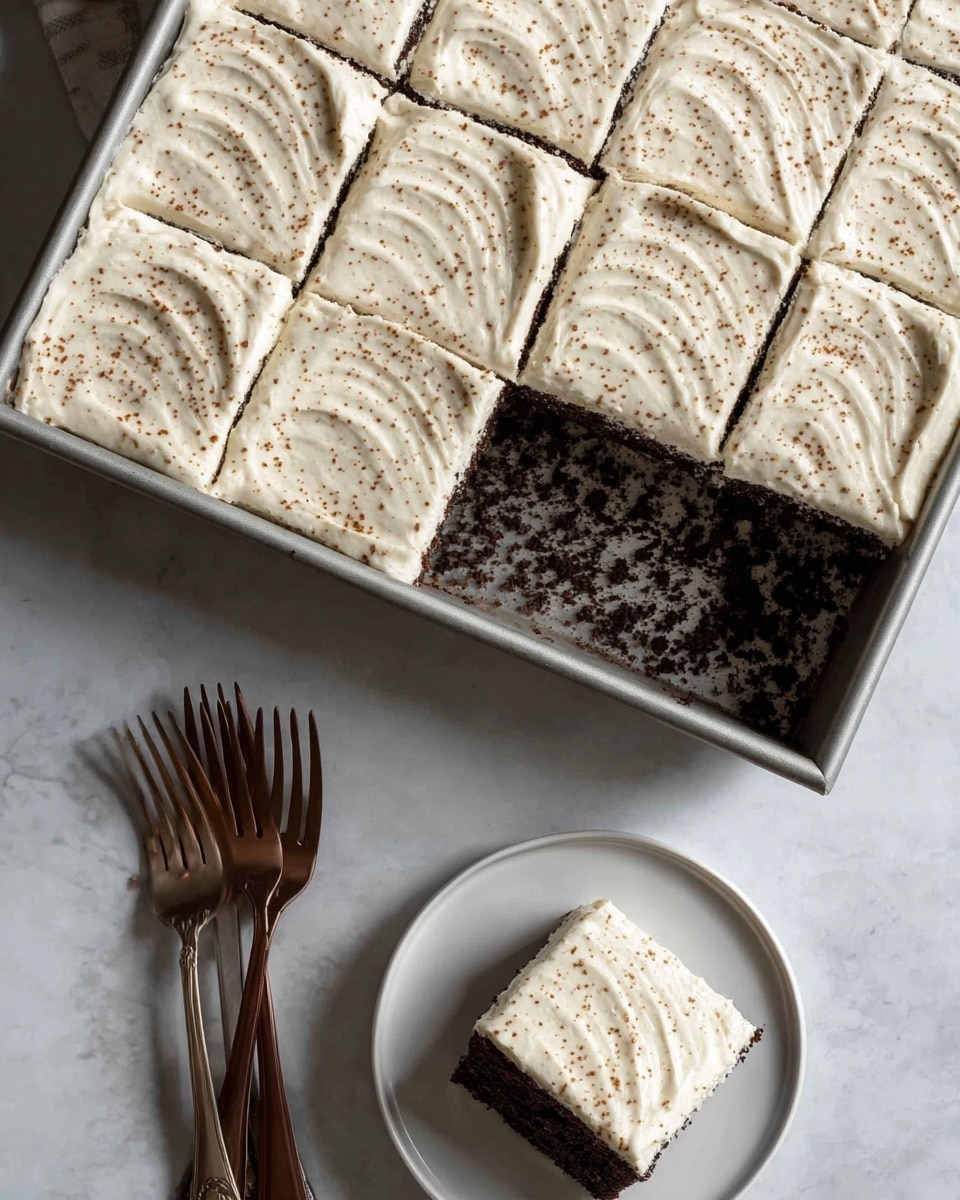 The image shows a rectangular cake in a metal pan, with eight square slices visible, one slice already taken out. The cake has two layers: a dark, crumbly chocolate base on the bottom and a thick, creamy white frosting on top, spread with smooth, wavy strokes. The frosting is sprinkled with small brown specks, giving it a textured look. In front of the pan, on a white plate, sits the removed slice showing the dark base and the thick white frosting clearly. Nearby, two brown forks rest on a white marbled surface. photo taken with an iphone --ar 4:5 --v 7