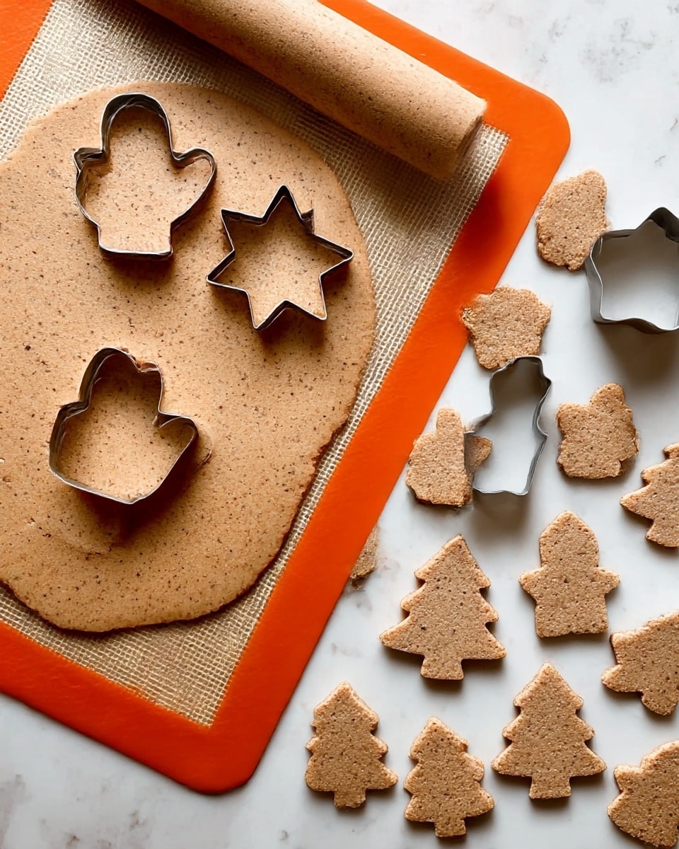 The image shows a rolled-out sheet of brown cookie dough with small darker specks, placed on an orange silicone mat with a white marbled texture surface underneath. Three cookie shapes are visible on the dough: a mitten, a star, and a Christmas tree, with metal cookie cutters inside the star and mitten shapes. On the right side, many raw cookies in mitten, star, and Christmas tree shapes are spread out evenly on a white marbled surface. The dough and cookies have a slightly rough texture with a light brown color and darker bits throughout. Photo taken with an iphone --ar 4:5 --v 7