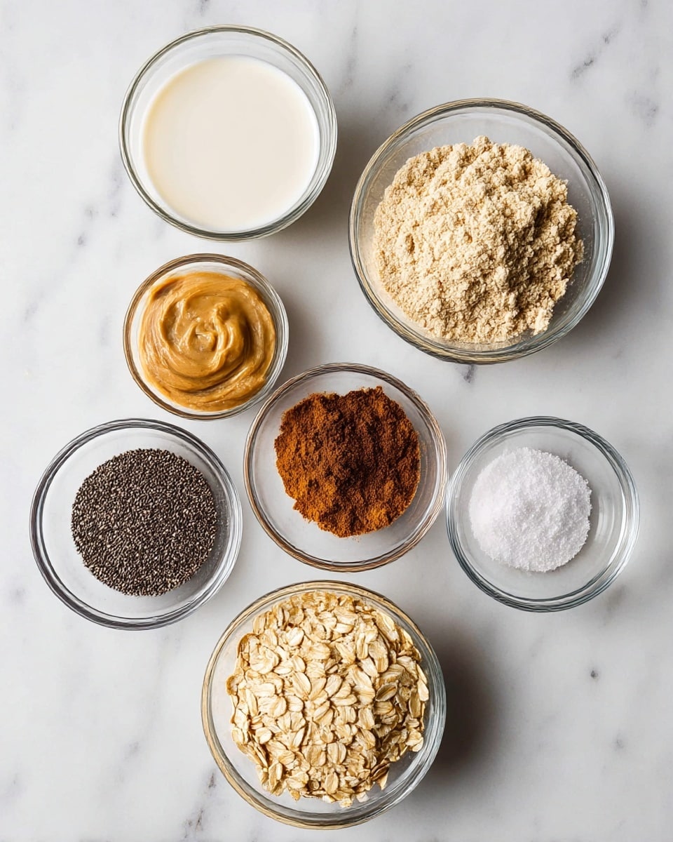 Seven small clear glass bowls are shown on a white marbled surface, each containing different ingredients. At the top left is a bowl filled with white almond milk, next to it on the right is a bowl of light brown peanut butter. Below the almond milk is a bowl with beige textured flour, while in the middle right is a bowl with dark orange cinnamon powder. Below the flour is a bowl of small black chia seeds, next to it on the right is a bowl with coarse white salt. To the right of the salt is a bowl of dark brown cocoa powder. At the bottom center is a bowl filled with light beige rolled oats. All bowls have a smooth, clear texture and hold dry and liquid ingredients arranged neatly. Photo taken with an iphone --ar 4:5 --v 7