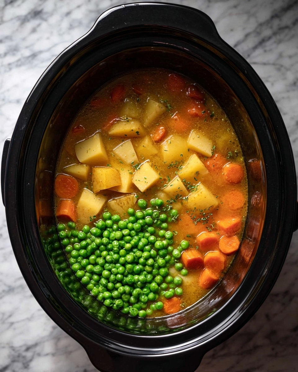 Inside a black slow cooker, a mixture of soft yellow-brown chunks of potatoes and pale yellow pieces of tofu sit beneath a layer of light orange carrot slices and small green celery bits, all in a golden broth. On one side, a pile of bright green peas rests on top of the broth, contrasting with the warm colors underneath. The slow cooker is set against a white marbled surface. photo taken with an iphone --ar 4:5 --v 7
