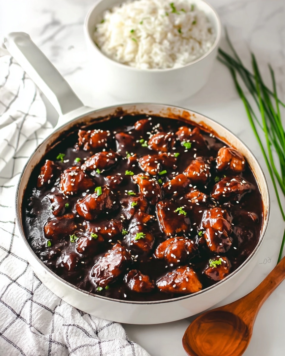 The image shows a white pan filled with dark brown sauce covered chicken pieces, glossy and thick in texture. The chicken pieces are small and spread evenly in the sauce, topped with small white sesame seeds and tiny green chopped herbs scattered across the surface. Behind the pan, there is a round white bowl full of fluffy white rice. A wooden spoon lies on a white checked cloth on the white marbled surface near the pan. There are some long green chives positioned in the background near the bowl. The whole scene is bright and clean. photo taken with an iphone --ar 4:5 --v 7