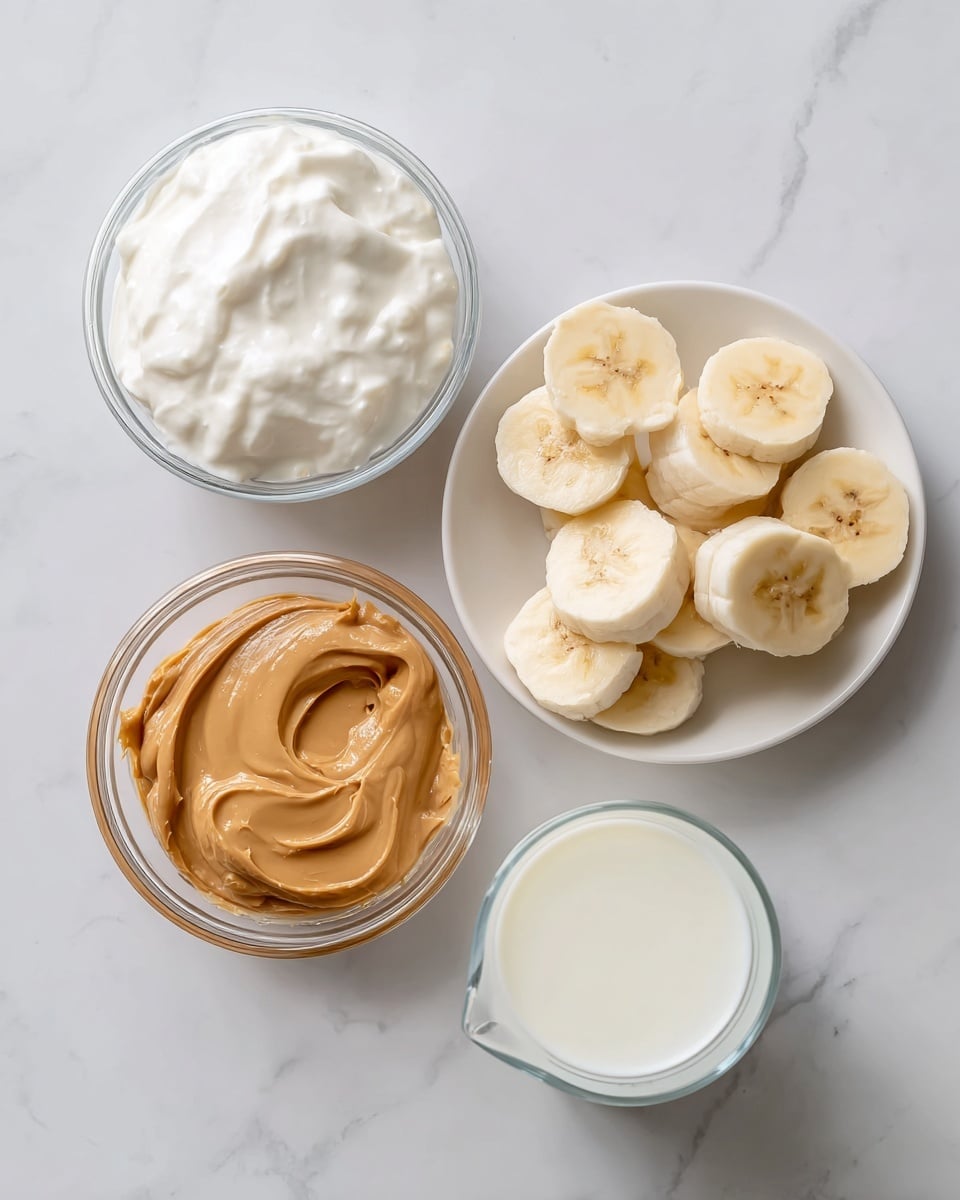 The image shows four separate clear containers on a white marbled surface. At the top left, there is a small glass bowl filled with thick, white Greek yogurt with a smooth creamy texture. Below it on the left side is a small glass bowl holding creamy light brown peanut butter with a shiny surface. To the right of peanut butter, there is a white plate with several thick, curved slices of pale yellow frozen banana arranged in a loose cluster. On the bottom right side, there is a small clear pitcher filled with white milk, showing a smooth liquid surface. The composition is clean and simple, with all containers spaced evenly. photo taken with an iphone --ar 4:5 --v 7