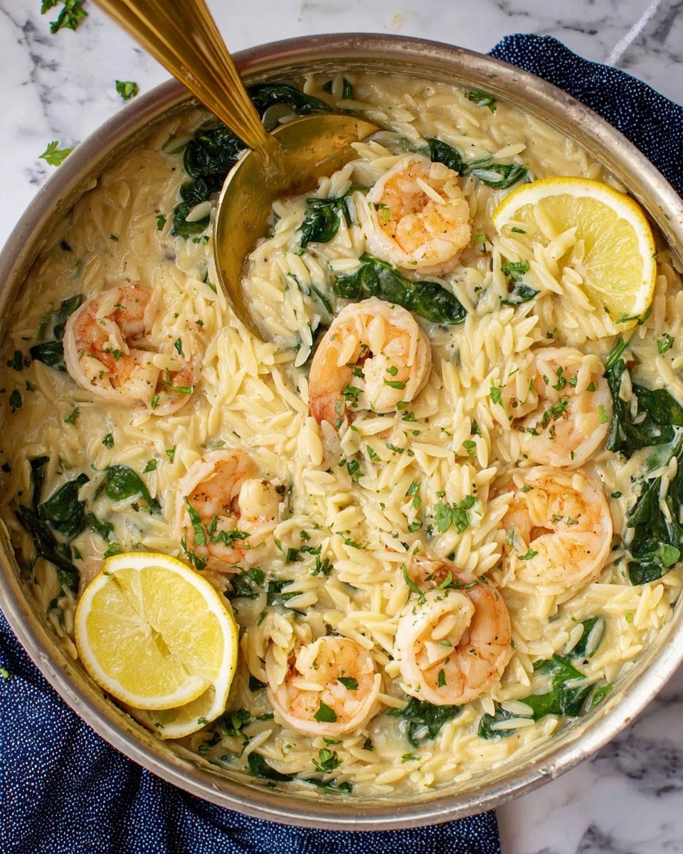 A close-up view of a pan filled with creamy orzo pasta mixed with cooked shrimp and green spinach leaves scattered throughout. The orzo is light golden with a smooth, slightly glossy texture. On top, there are six plump, pink shrimp placed evenly, some partially submerged in the creamy sauce. Two thin lemon slices rest on the surface of the dish, adding a fresh yellow color contrast. Small flakes of green herbs are sprinkled over everything. A golden spoon rests inside the pan, partially lifting some of the orzo and spinach. The pan sits on a white marbled surface with a blue cloth beneath it. Photo taken with an iphone --ar 4:5 --v 7