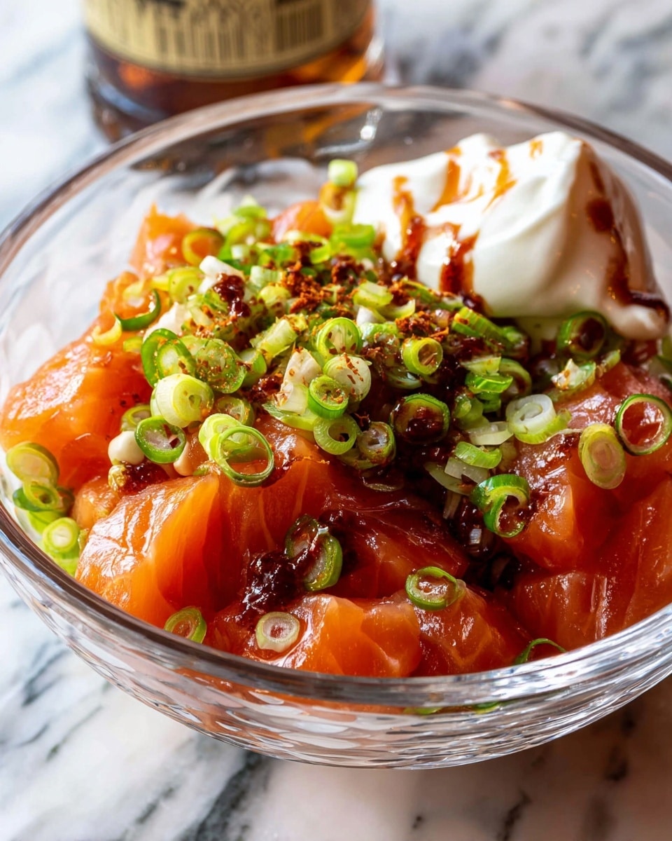 A clear glass bowl filled with large chunks of fresh, bright orange salmon at the bottom, topped with a generous amount of thinly sliced green onions scattered all over. There is a dollop of smooth white mayo placed on one side of the bowl, partially covered with a dark reddish-brown spicy sauce drizzled on top of the mayo and green onions. The bowl sits on a white marbled surface with a blurred bottle in the background. photo taken with an iphone --ar 4:5 --v 7