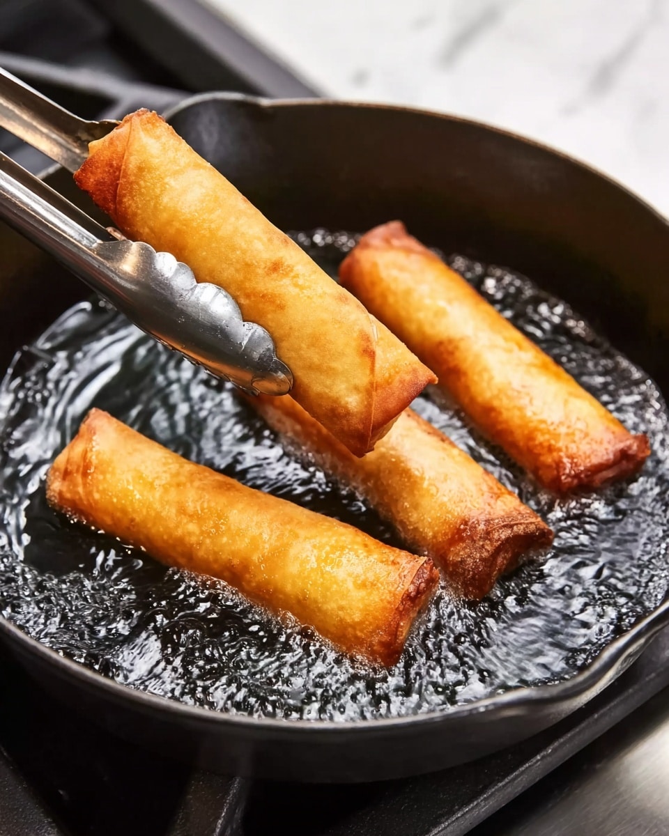 A black cast iron pan holds three golden brown spring rolls frying in shimmering hot oil, with the top spring roll being gently held and flipped by silver metal tongs, showing a crispy textured surface. The stove beneath the pan has a white marbled background, creating a clean and bright contrast. The spring rolls are evenly spaced, with the pan filled with bubbling oil that reflects light, giving a fresh and hot cooking scene photo taken with an iphone --ar 4:5 --v 7
