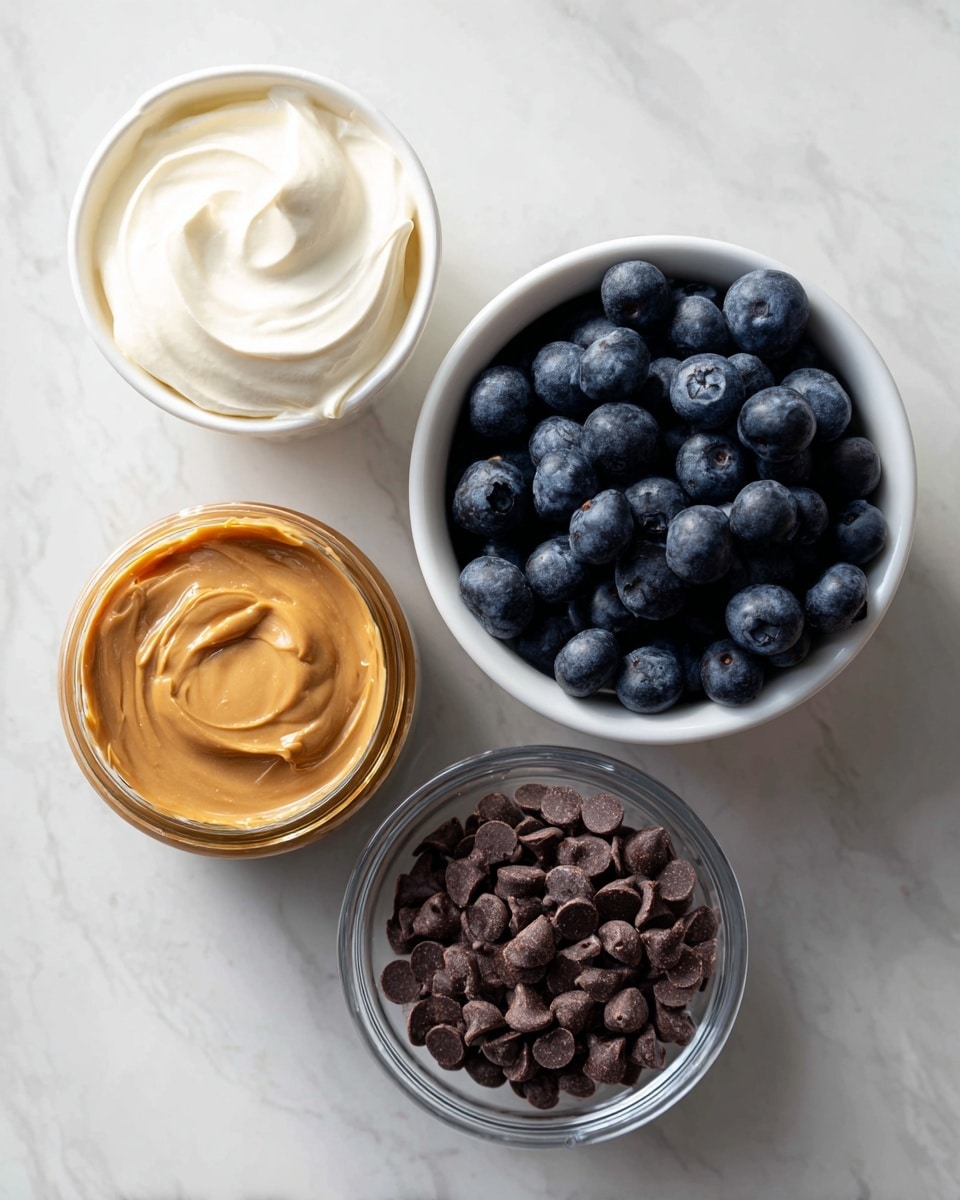 The image shows four containers of ingredients arranged on a white marbled surface. On the top left, there is an open yogurt cup with creamy white yogurt inside, next to a white bowl filled with fresh, dark blue blueberries. Below the yogurt, there is a small open jar of smooth peanut butter with a shiny, light brown texture. To the right of the peanut butter, there is a clear glass bowl filled with small, dark brown chocolate chips. The ingredients are neatly spaced and the lighting is bright and natural, highlighting the colors and textures clearly. Photo taken with an iphone --ar 4:5 --v 7
