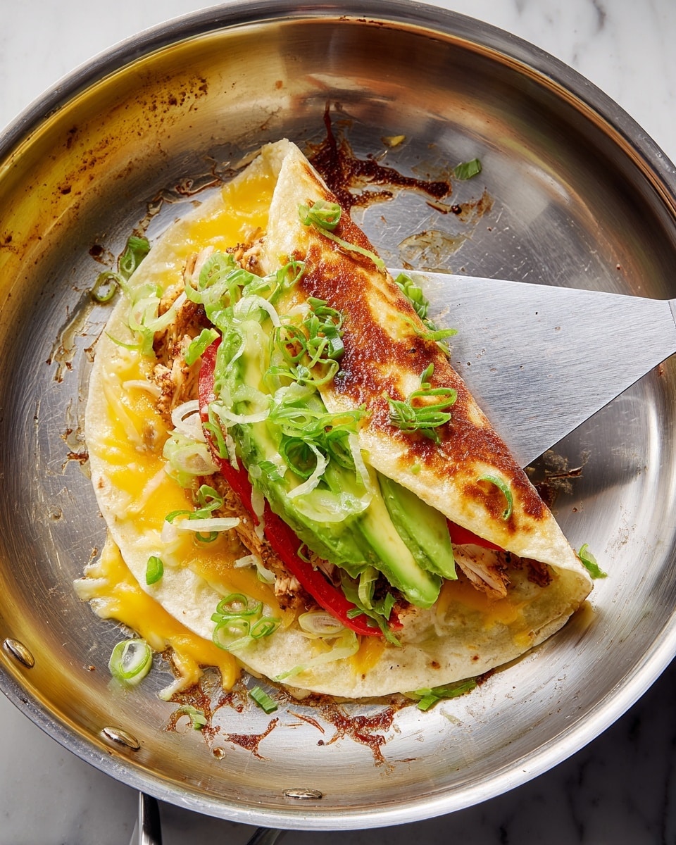 A soft tortilla is folded in half inside a silver pan, showing its colorful layers inside. The bottom layer has melted yellow cheese spread on the tortilla, topped by a well-cooked browned chicken piece. Above the chicken, there are thin red pepper strips scattered, followed by three layers of sliced green avocado. The topmost layer is chopped green onions sprinkled all around. A metal spatula is lifting the tortilla gently from the pan. The pan has a shiny, slightly scratched surface with some oil around the food. The background is a white marbled texture. photo taken with an iphone --ar 4:5 --v 7