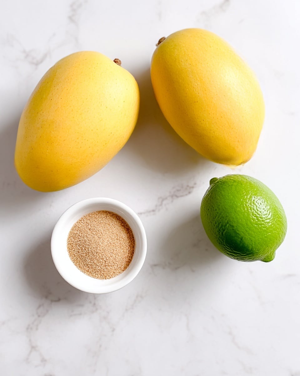 The image shows two whole yellow mangoes with smooth skin placed on a white marbled surface. Near them is a small white bowl filled with a light brown sweetener, and beside it is a whole green lime with a smooth texture. The arrangement is simple, with the mangoes positioned diagonally, the sweetener bowl on the right, and the lime towards the bottom right. photo taken with an iphone --ar 4:5 --v 7