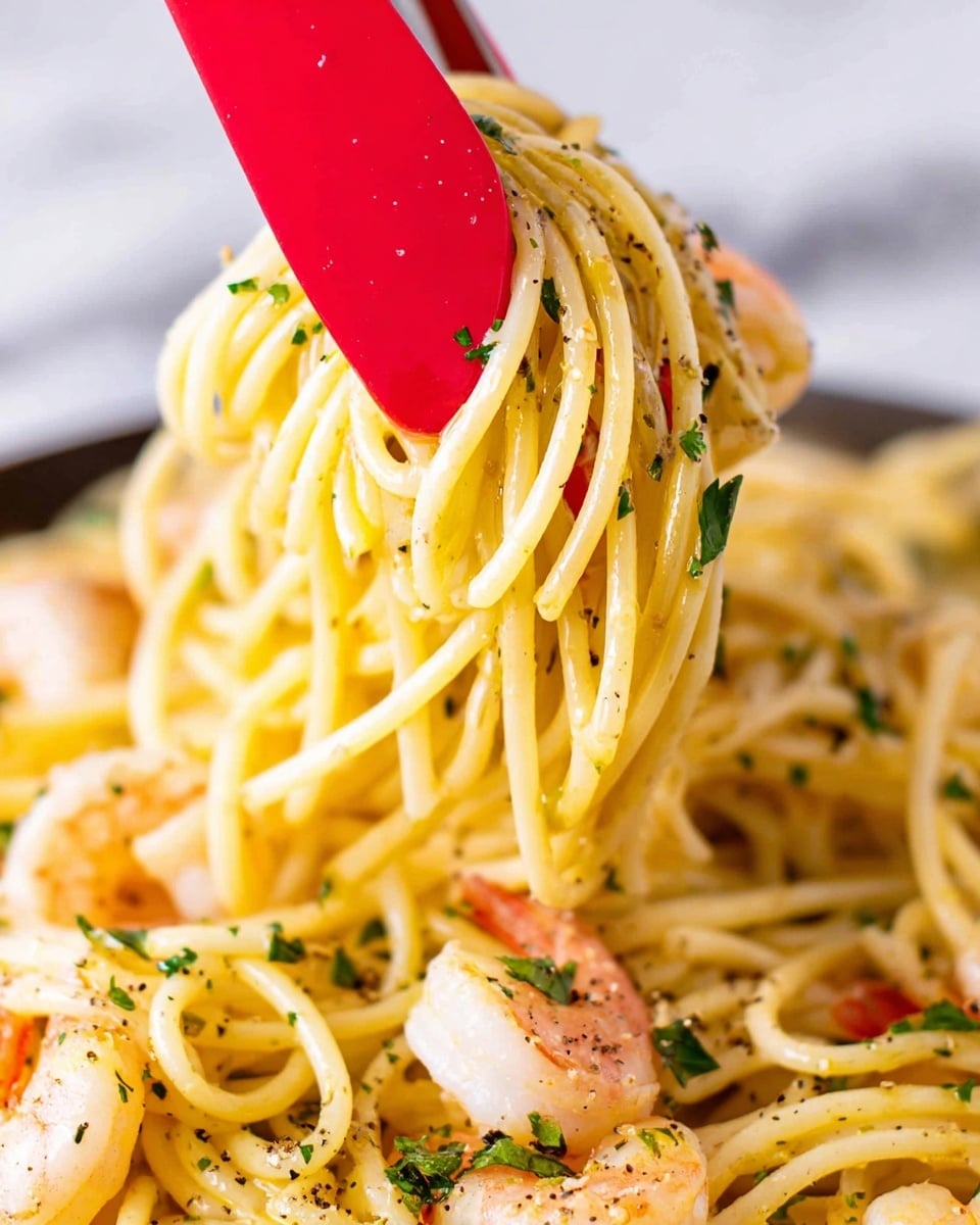 A close-up view of a pile of creamy yellow spaghetti noodles mixed with small pink shrimp, speckled with green parsley flakes and black pepper. The noodles are lifted by metal tongs with a bright red silicone tip, showcasing the smooth texture and slight shine of the pasta. The background is a white marbled surface, enhancing the colors of the food without distraction. photo taken with an iphone --ar 4:5 --v 7